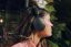 Woman sitting outside on a patio with plants wearing a black Sonos Ace Ultra headphones