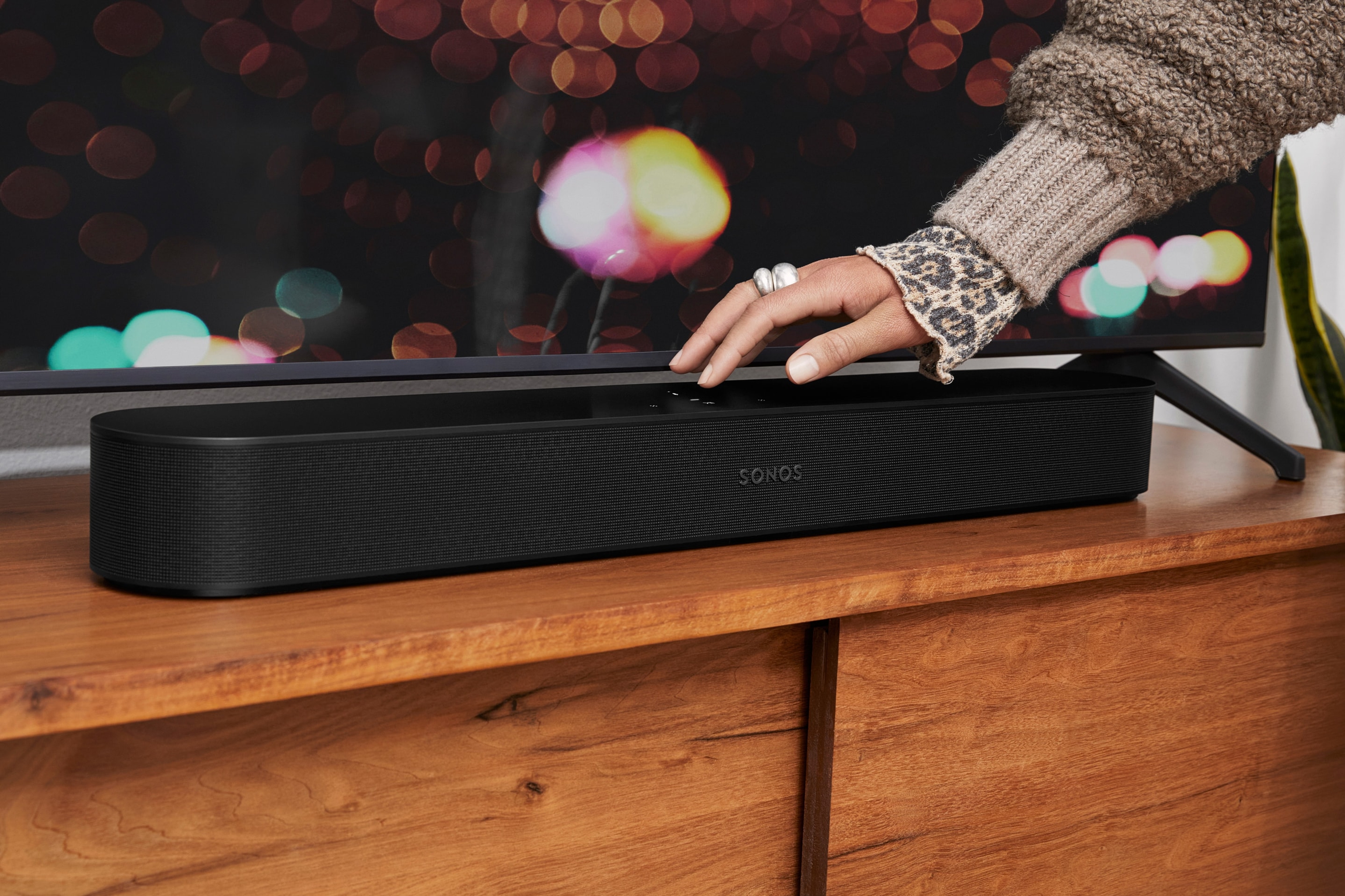 Person using touch controls on a black Beam soundbar