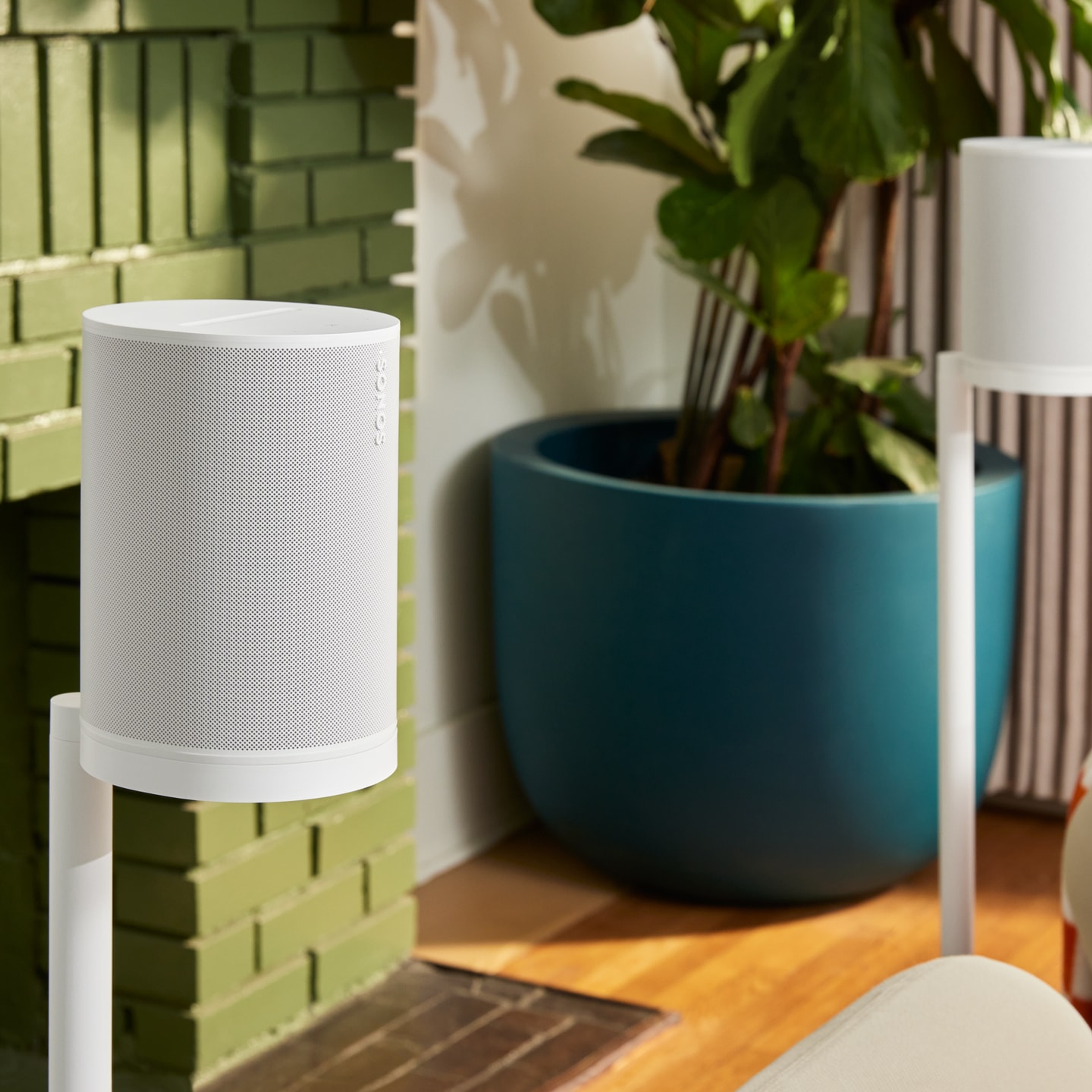 Une paire de haut-parleurs Sonos Era 100 SL blancs sur leurs supports respectifs, utilisés comme composants ambiophoniques dans un salon