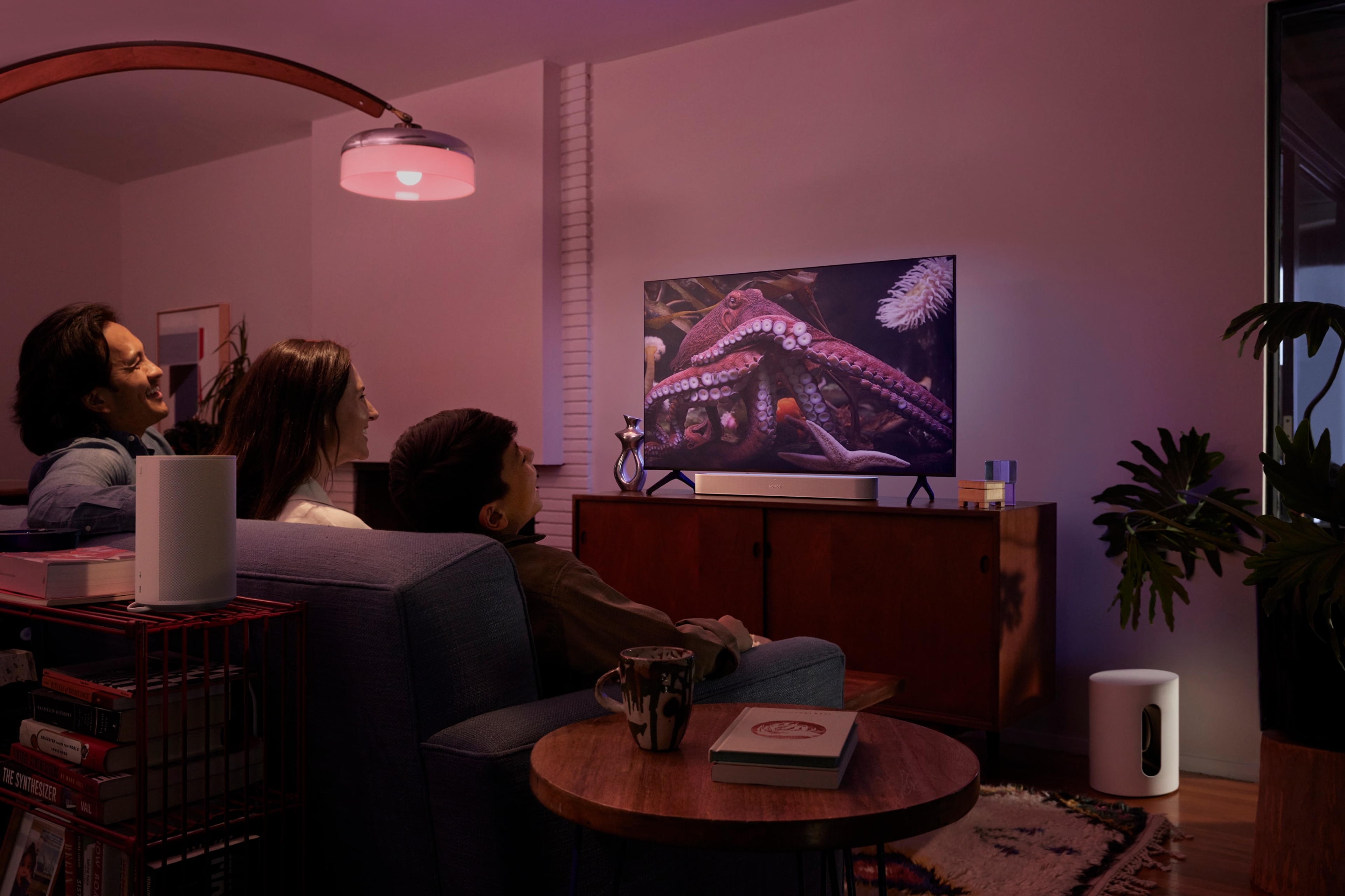 Une famille sur un canapé en train de regarder un documentaire animalier avec un système home cinéma Sonos comprenant une Sonos Beam, un Sonos Sub Mini et des Sonos Era 100