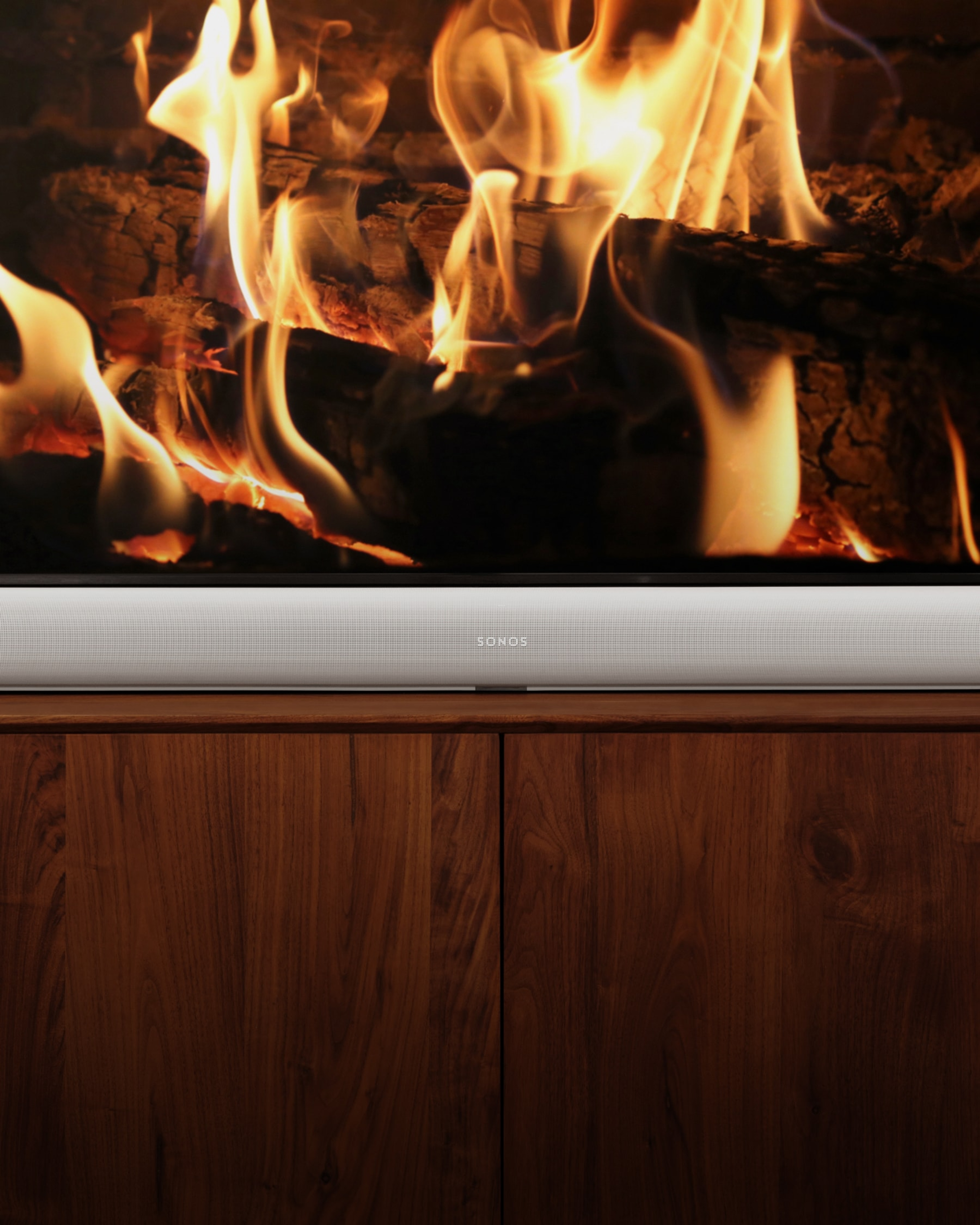 White Sonos Arc Ultra placed below a TV displaying a fireplace