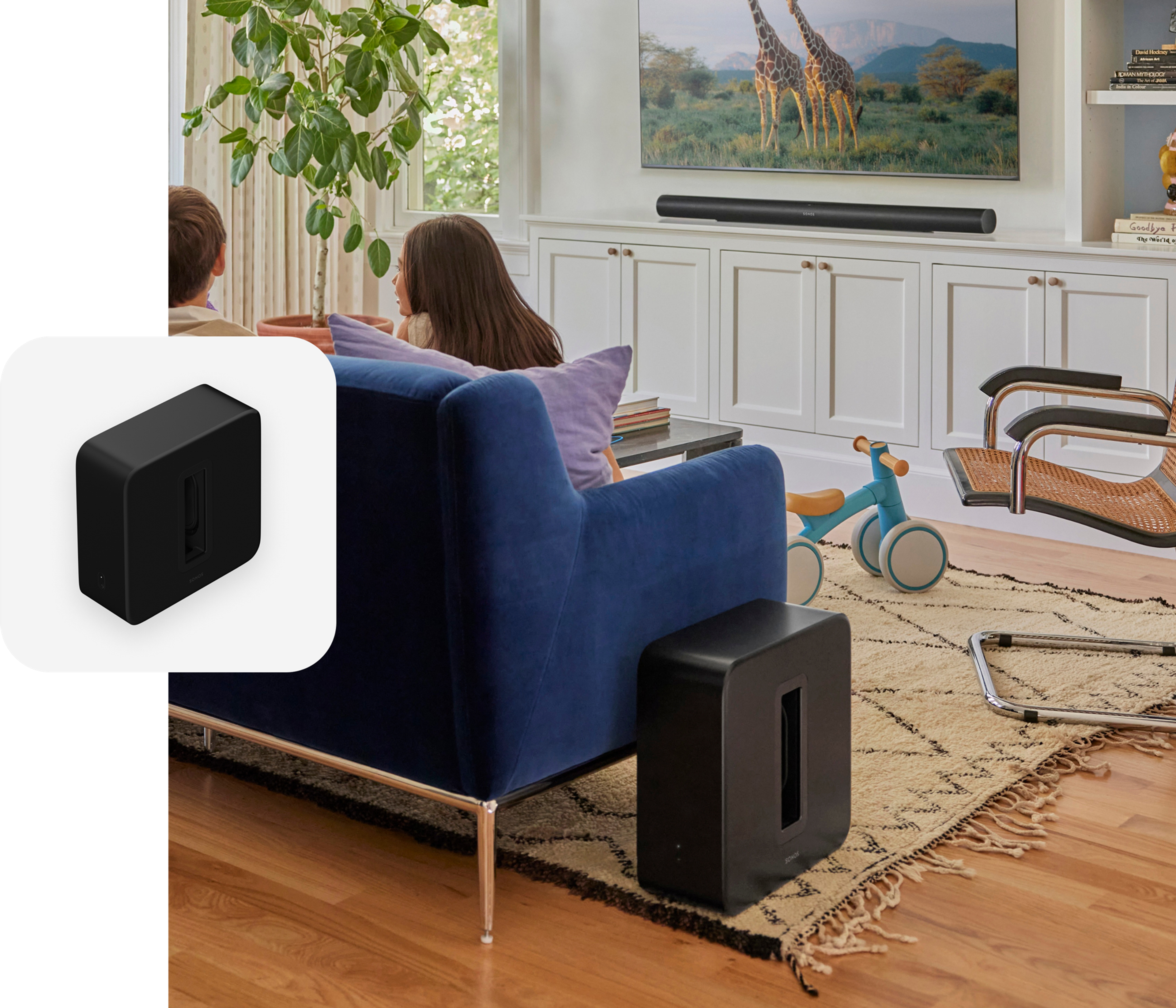 Kids sitting on a blue couch in the living room with black Sonos Sub 4 and Arc Ultra and a black Sub 4 product tile overlay