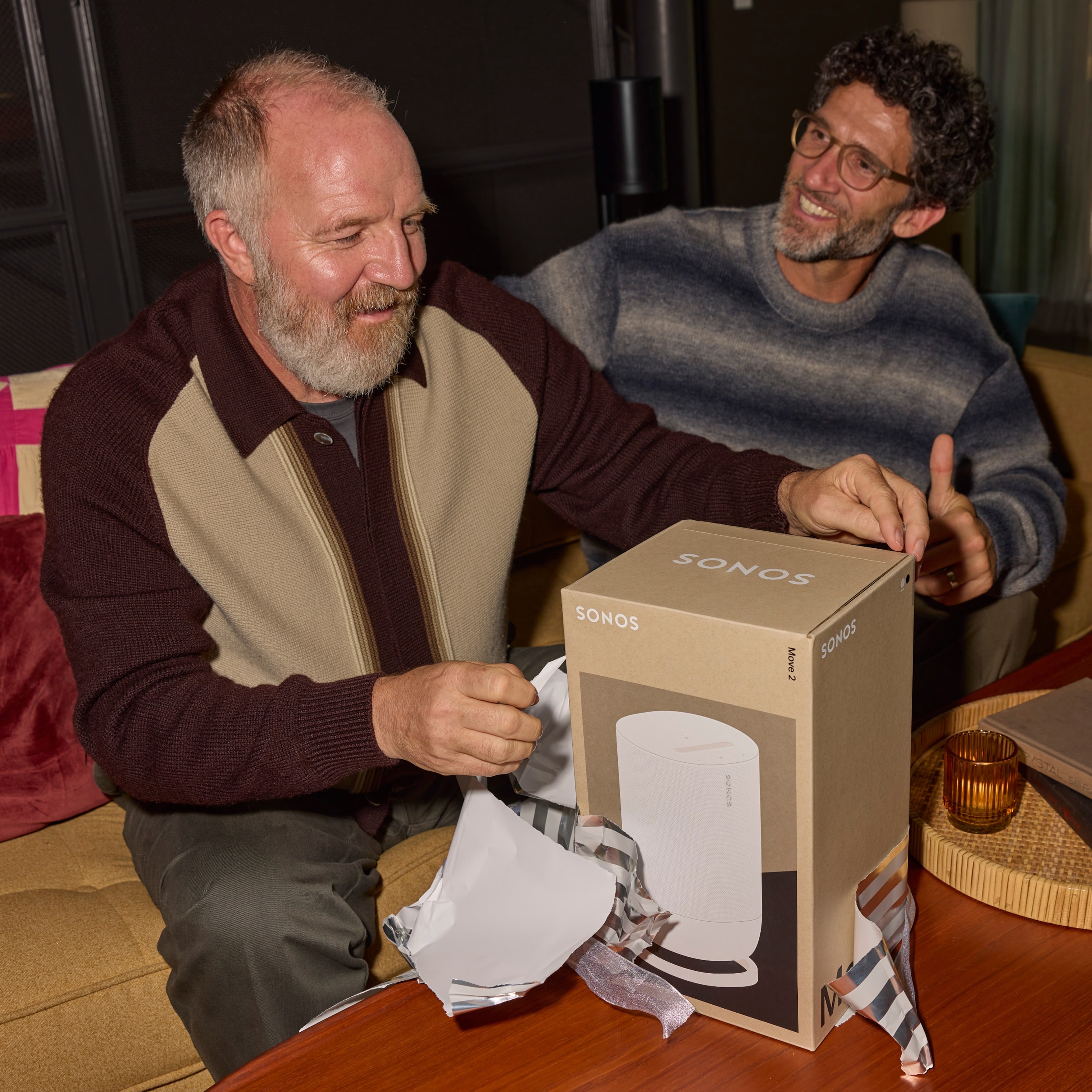 Two people smiling and opening a gift wrapped Sonos Move 2