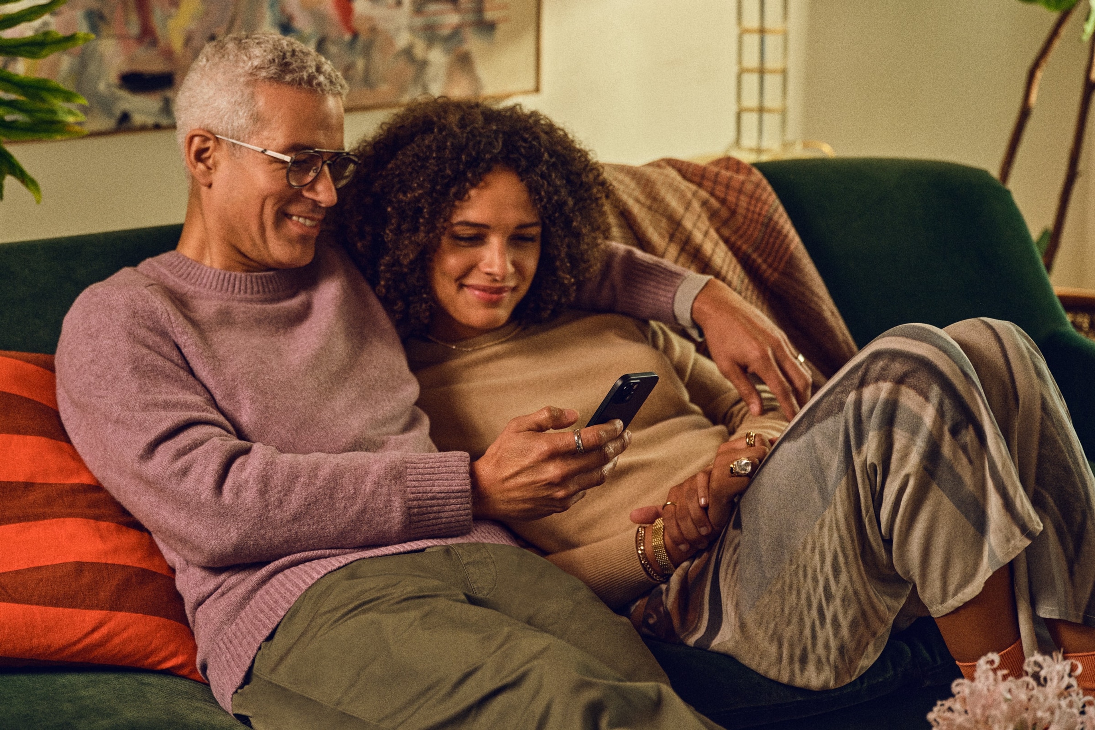 Una pareja sentada en un sofá usando la app Sonos