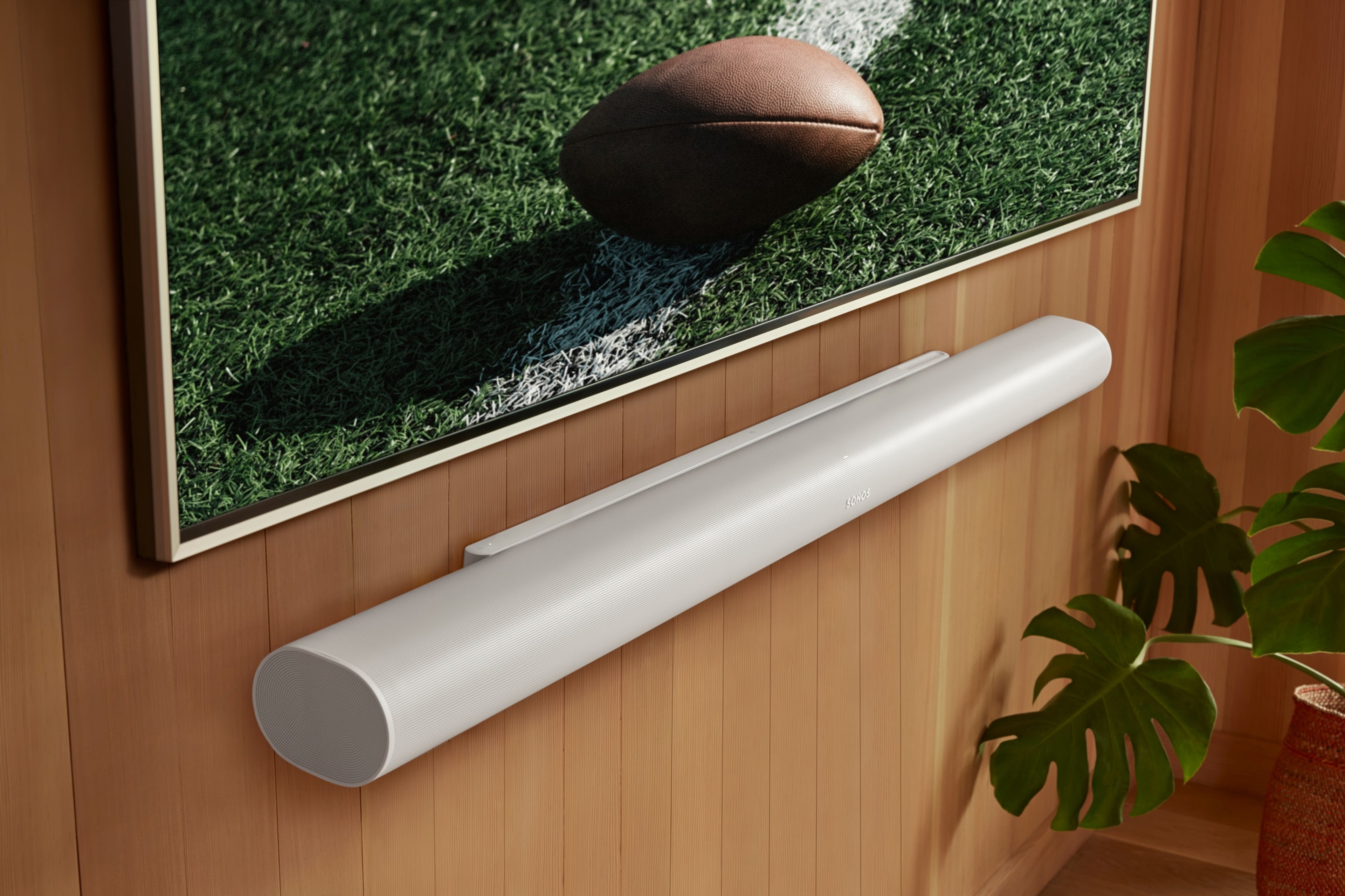 A white Sonos Arc Ultra mounted under a TV showing a football game