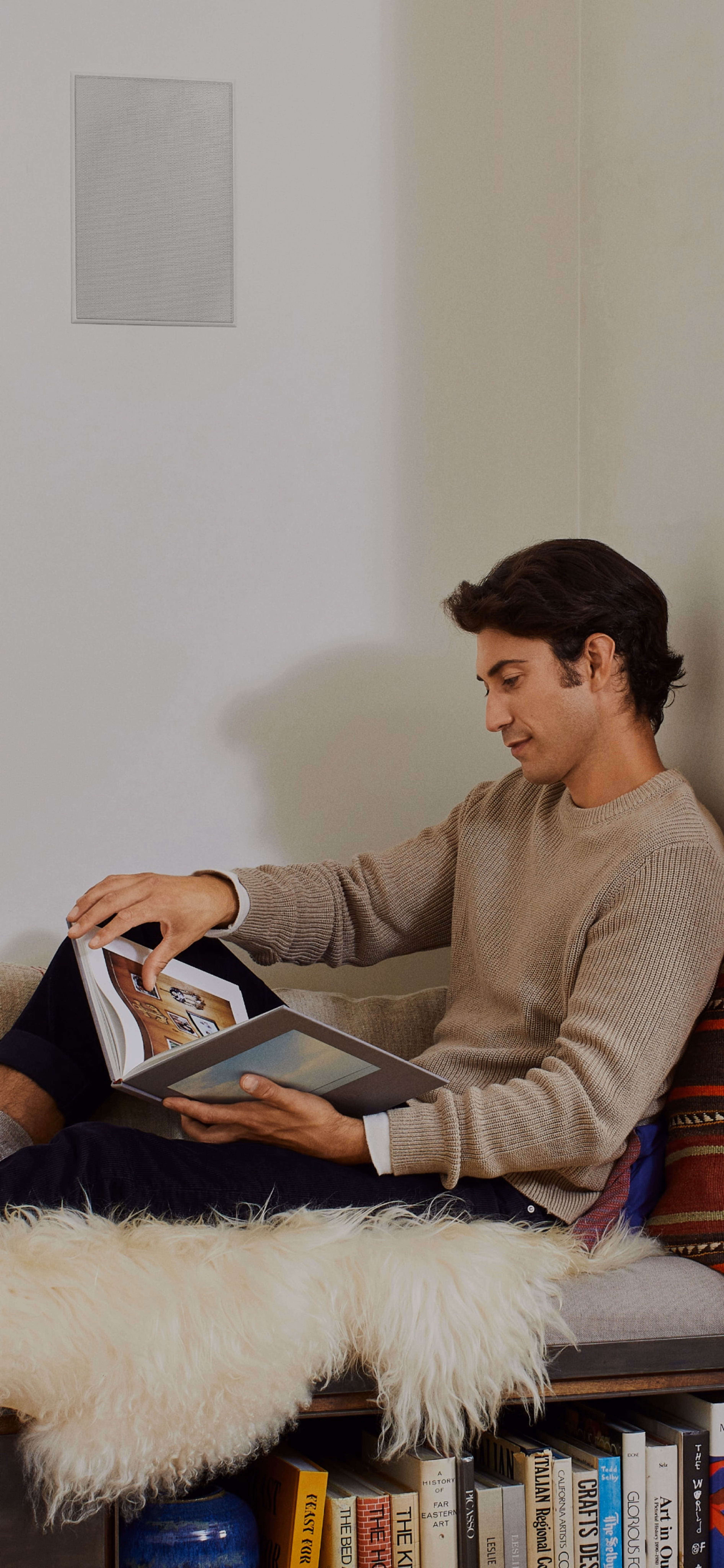 Person reading below their installed Sonos and Sonance In-Wall speakers