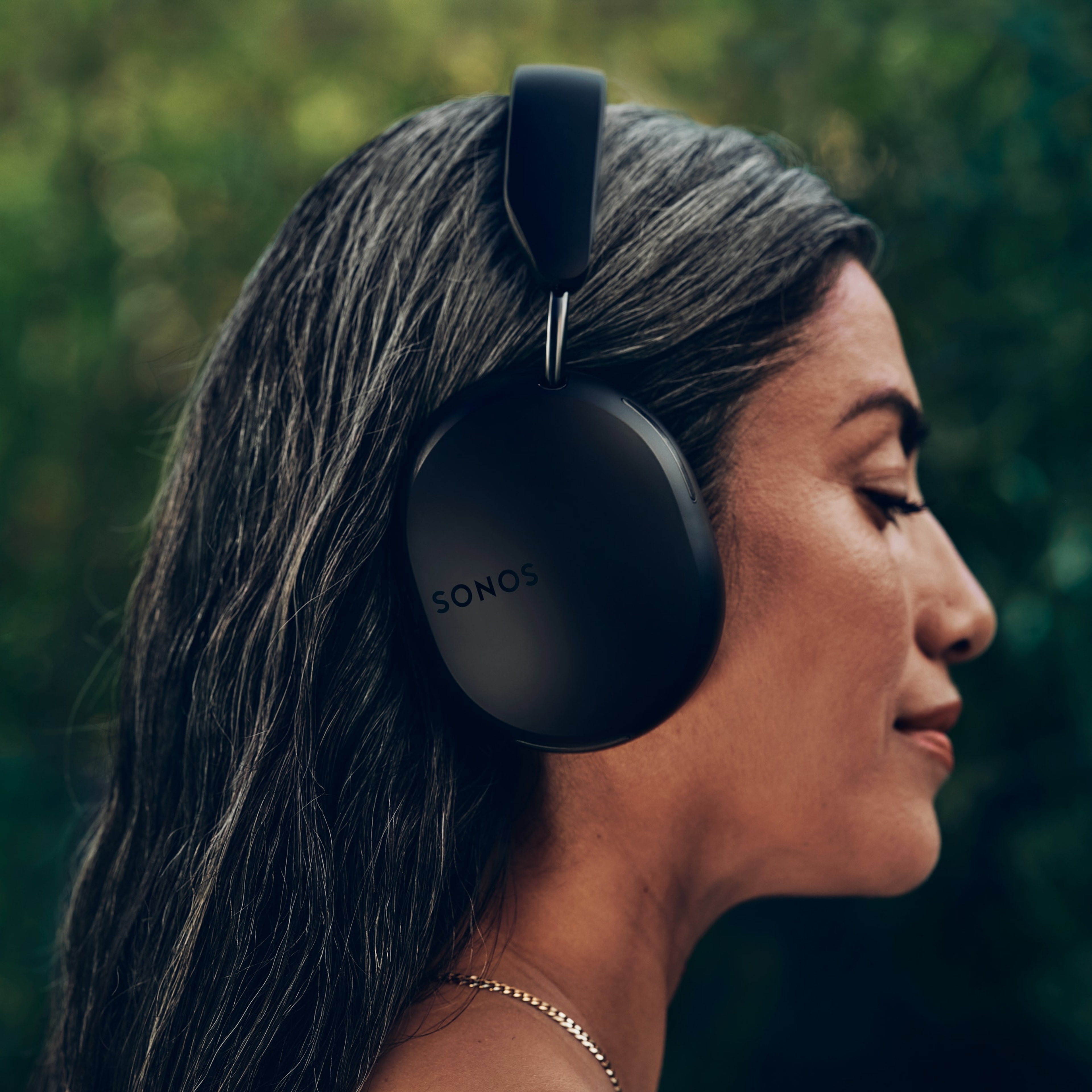 Side profile of female user wearing a pair of black Sonos Ace headphones