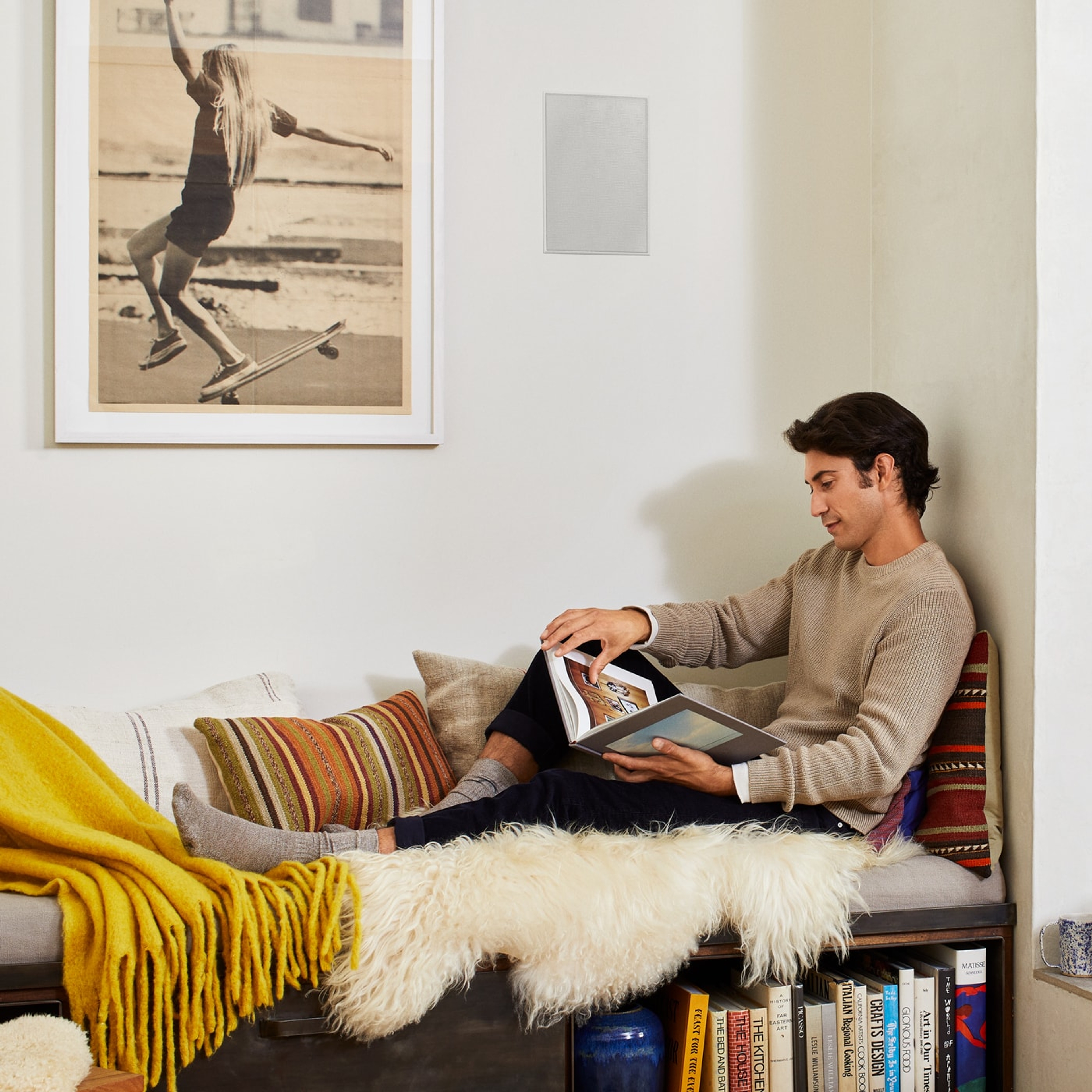 Person reading next to an installed in-wall speaker by Sonos and Sonance