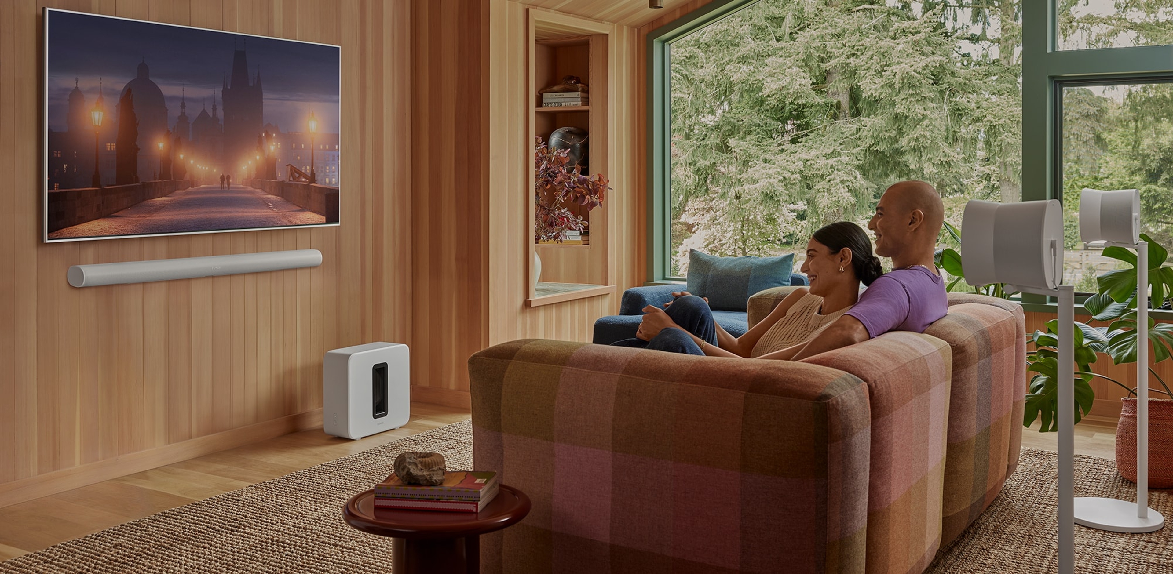 Couple watching tv with a wall mounted white Arc Ultra, Sub 4 and pair of Era 300 surrounds
