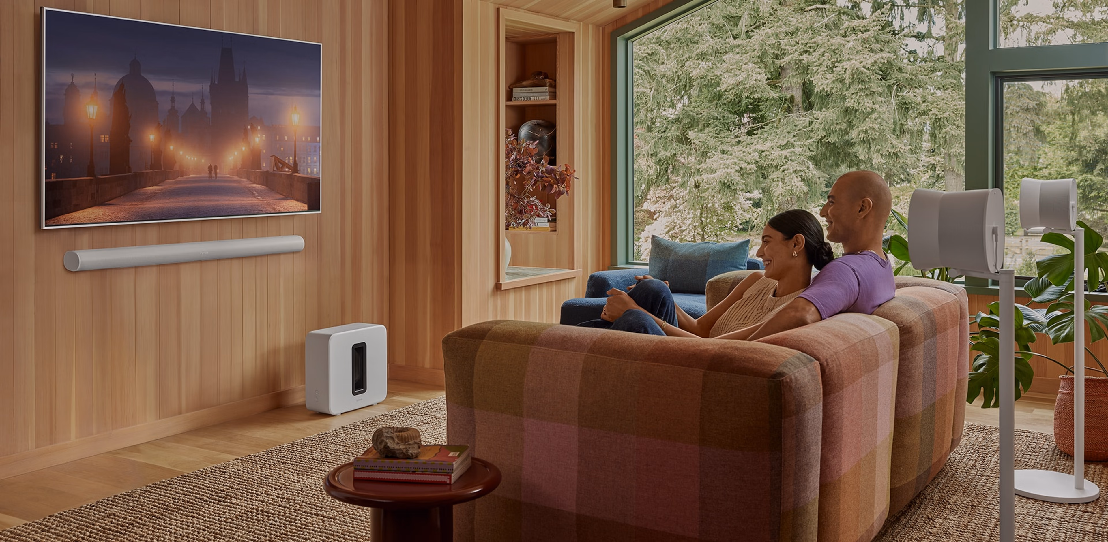 Couple watching tv with a wall mounted white Arc Ultra, Sub 4 and pair of Era 300 surrounds