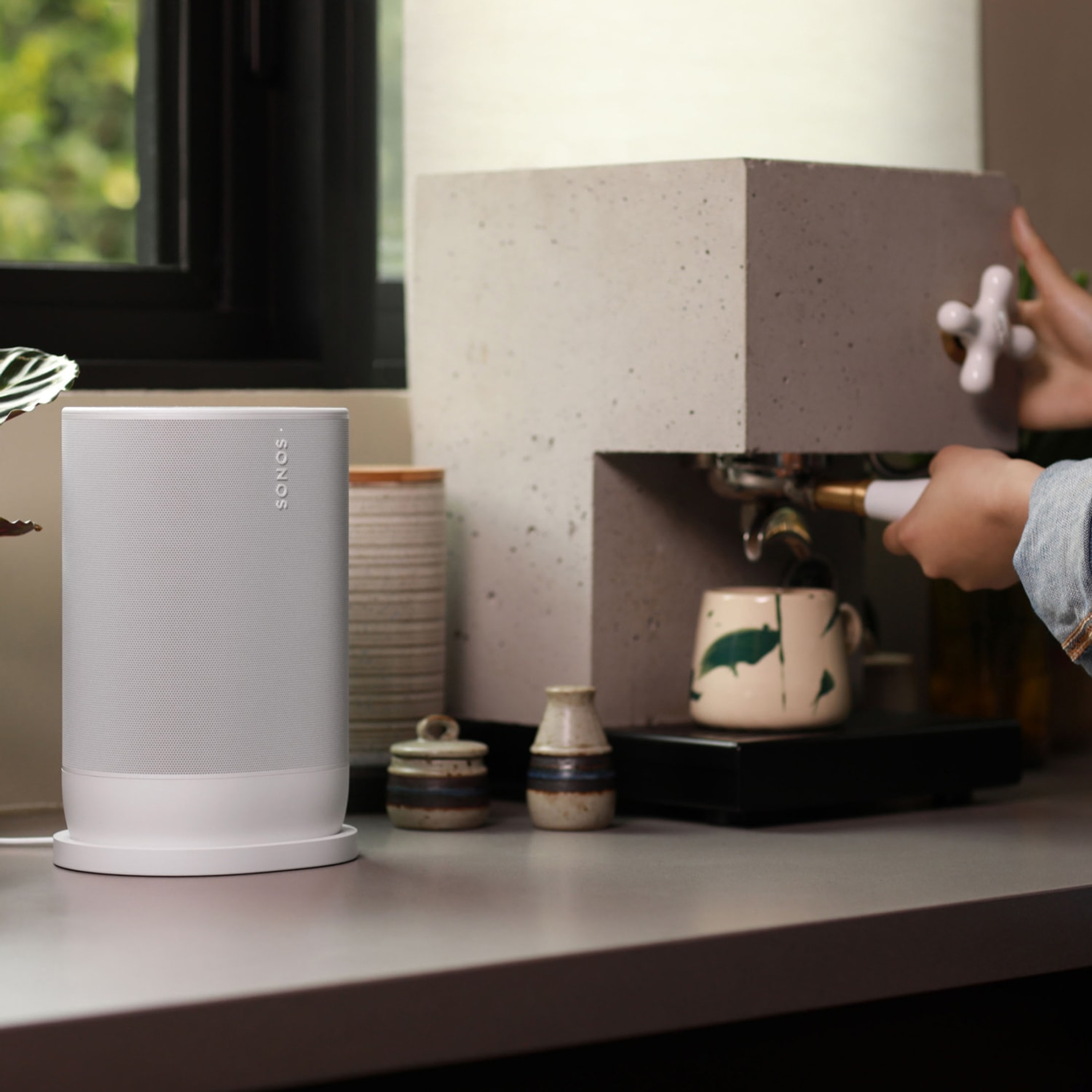 Foto einer Frau, die an einer Küchenanrichte neben einem Sonos Move 2 in Weiß Espresso kocht