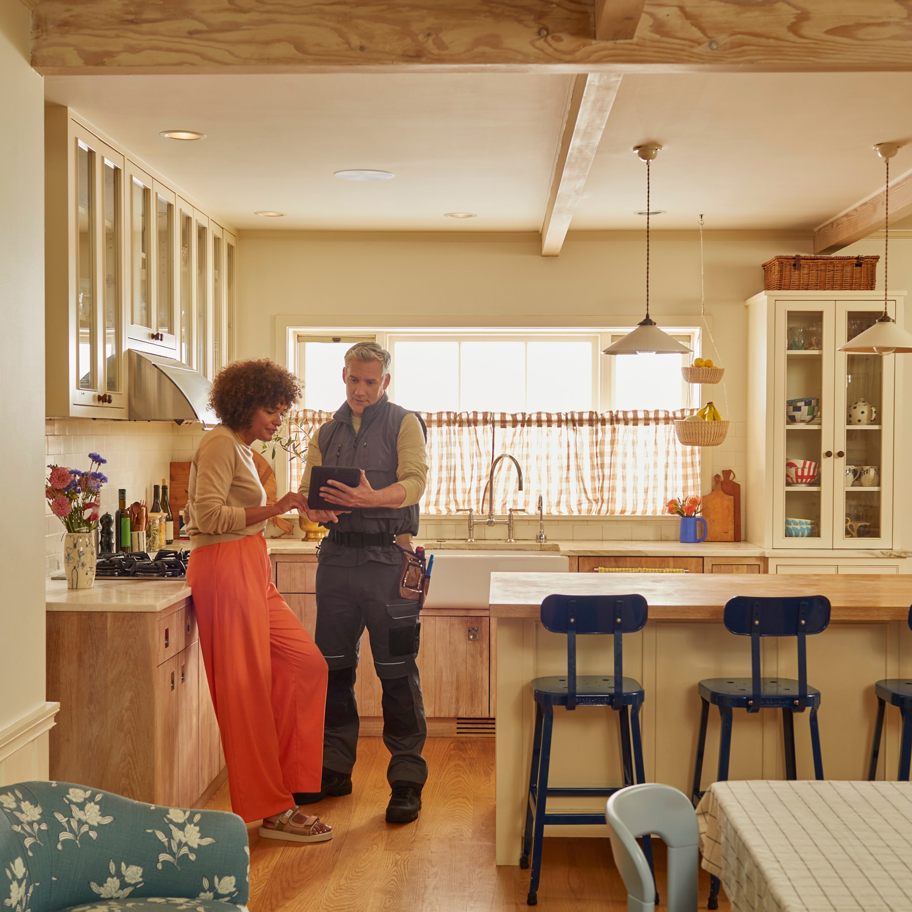 Un installateur certifié présentant l'application Sonos à un client dans une cuisine équipée d'enceintes In-Ceiling.