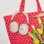 Sonos Ace Ultra headphones in Sand hanging on a red tote bag