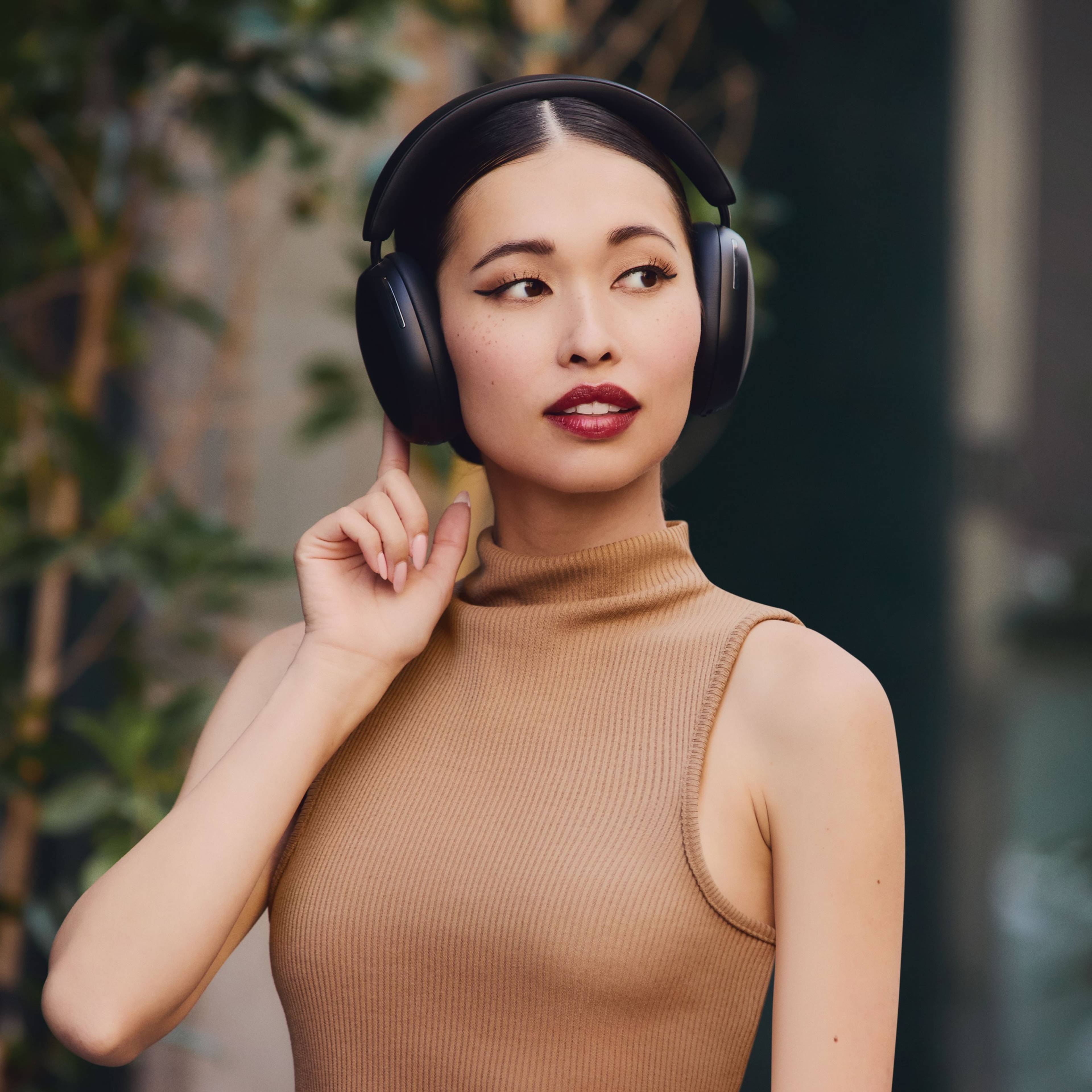 Person using the controls on black Sonos Ace headphones while outside