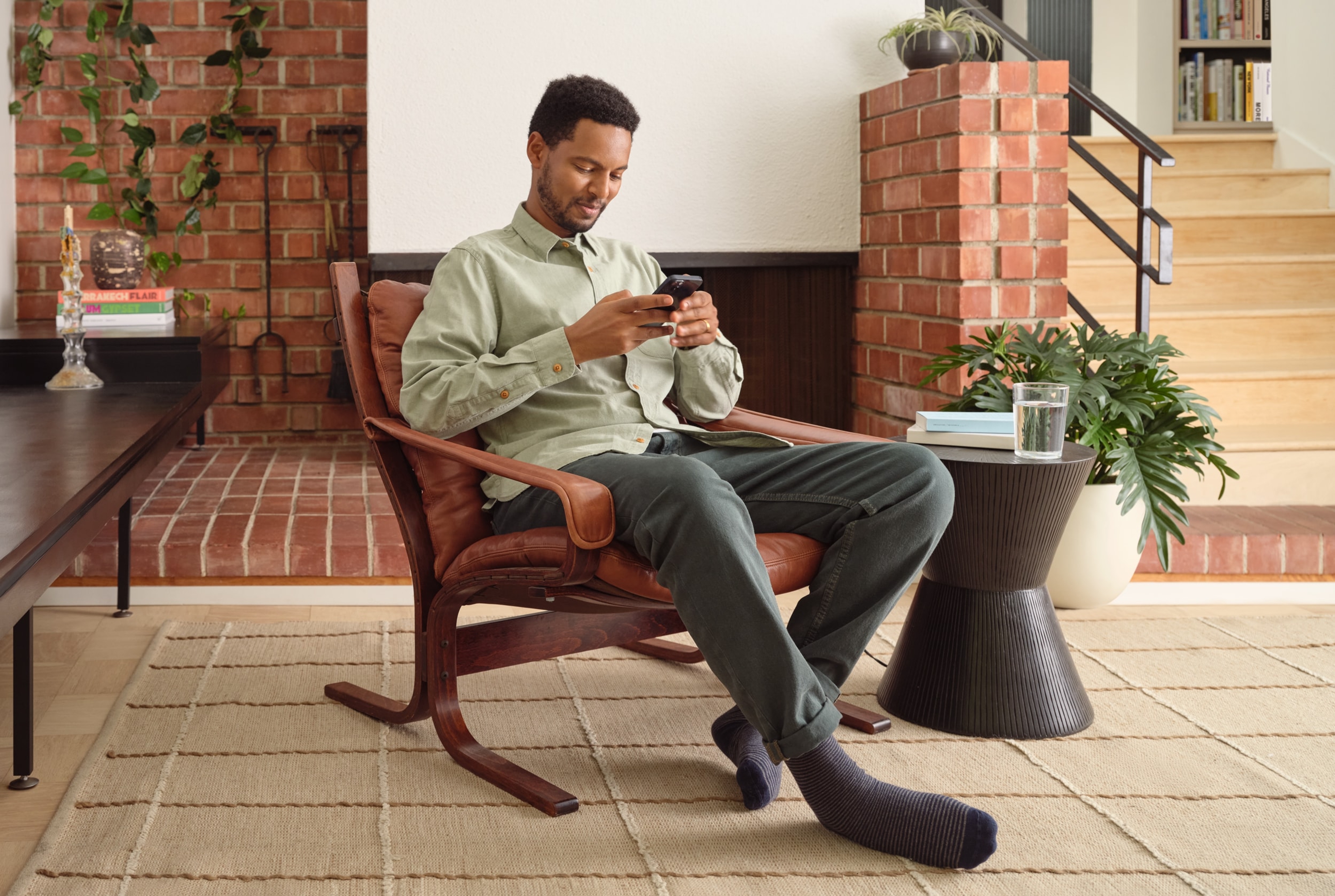 Eine sitzende Person, die die Sonos App auf einem Smartphone nutzt