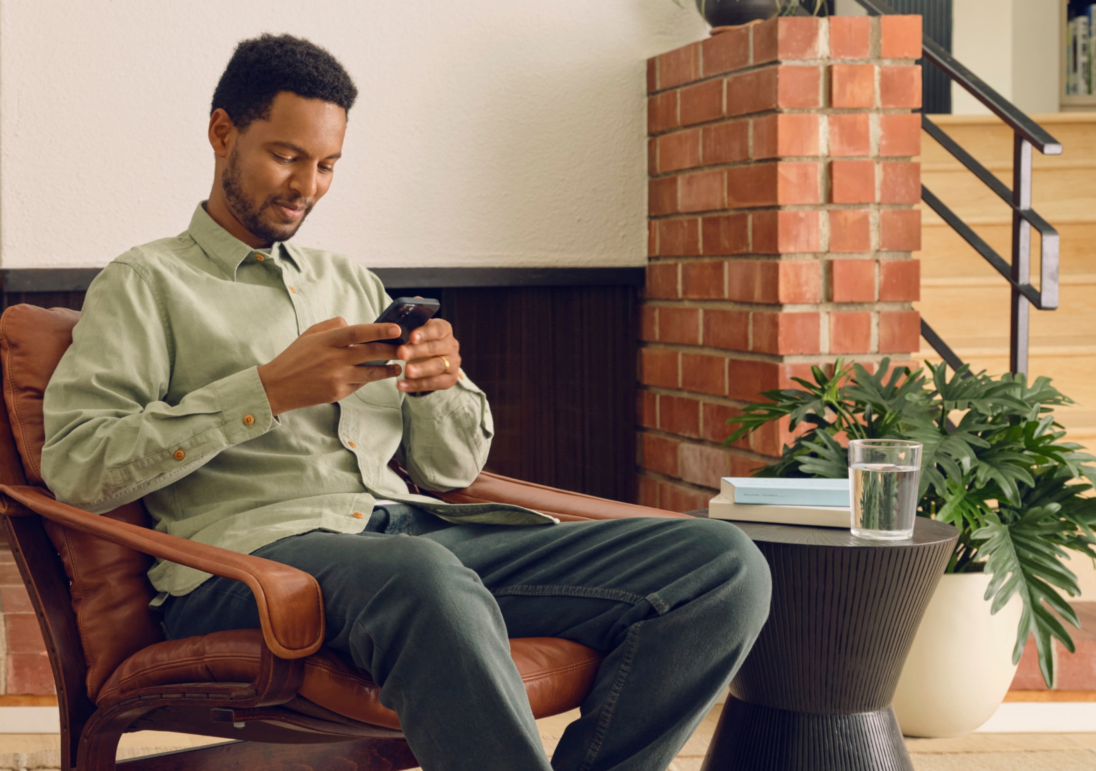 Utilisateur de l’application Sonos au téléphone, assis dans son salon