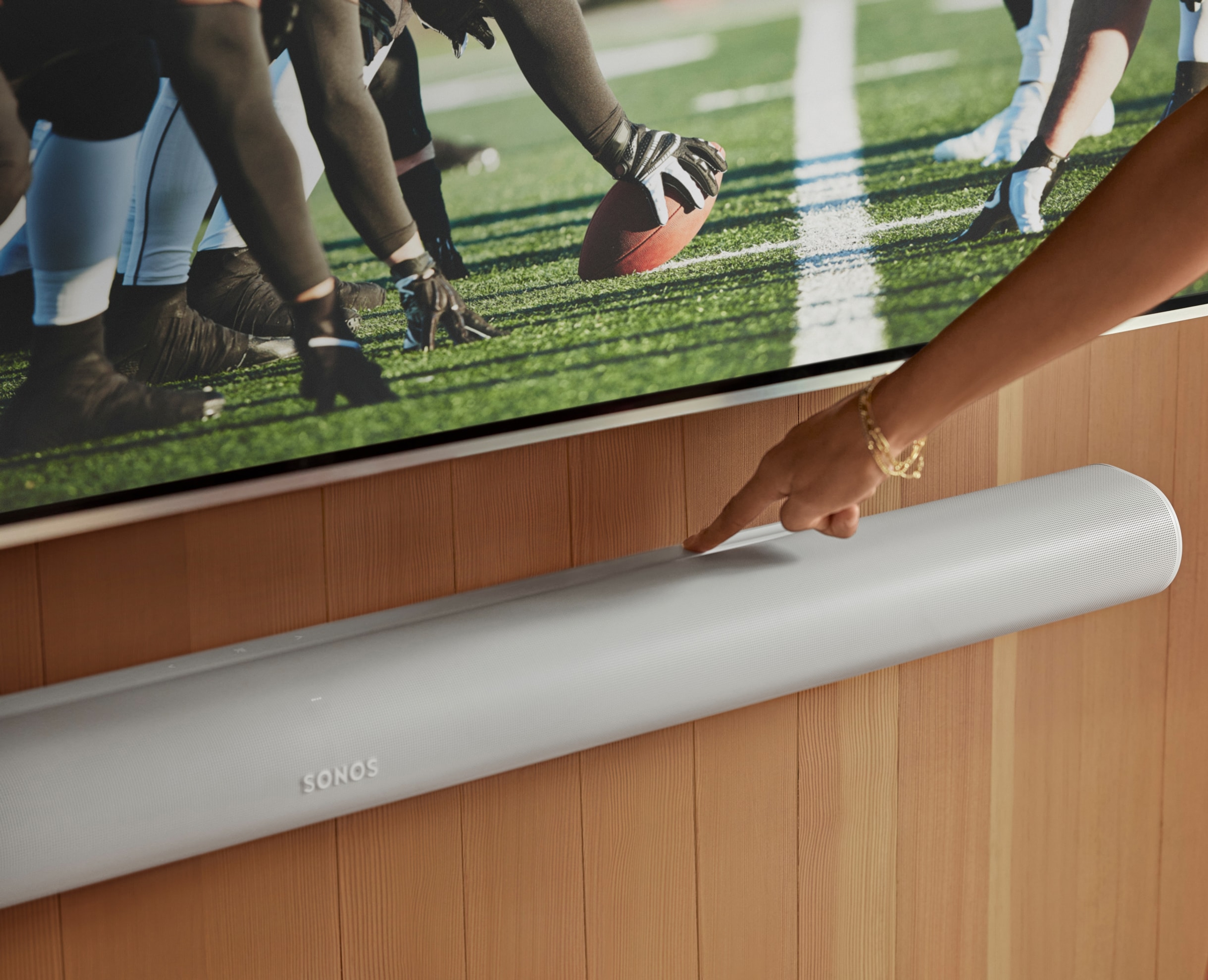 User adjusting the touch controls on their white Arc Ultra soundbar while watching football
