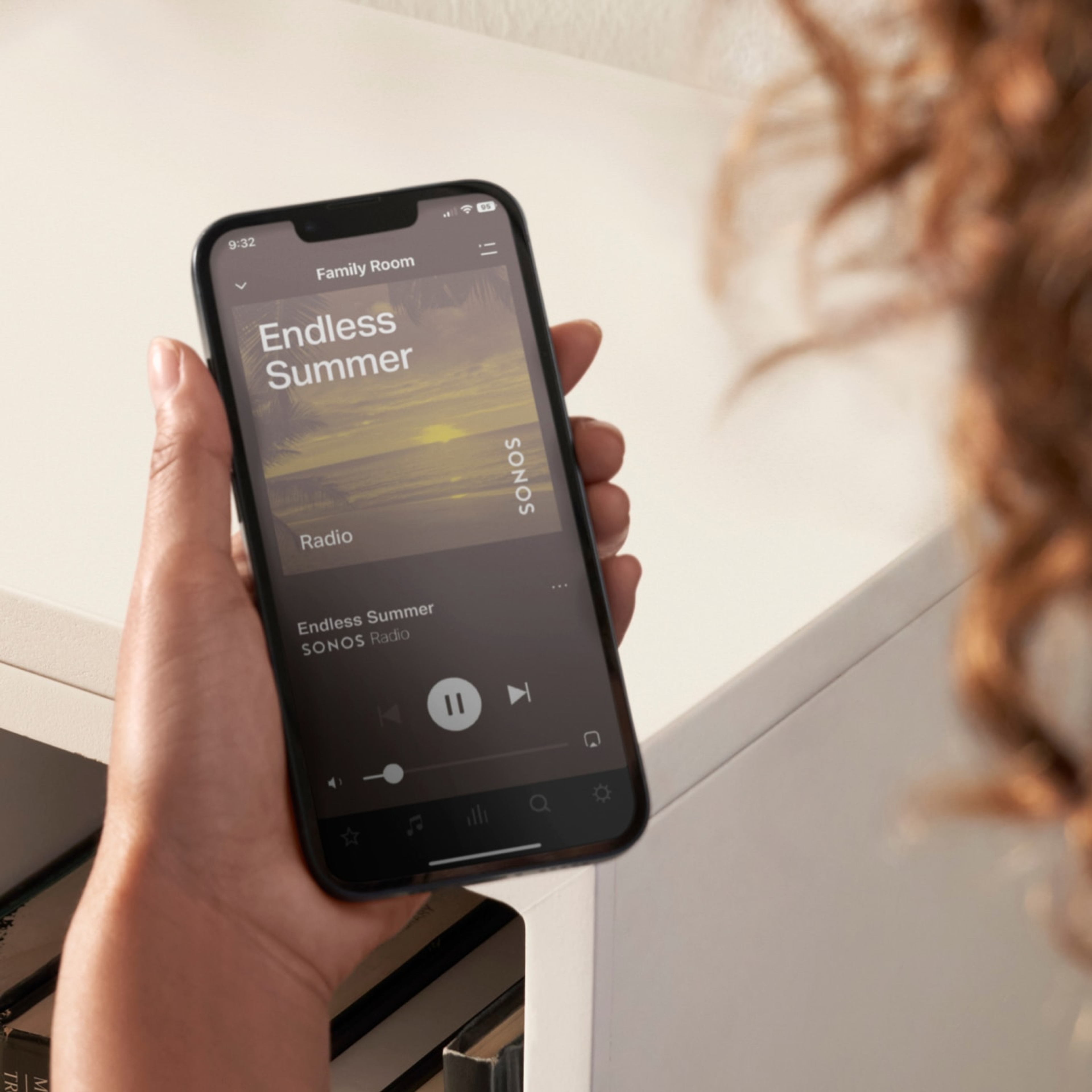 Gros plan sur le smartphone d'un utilisateur se servant de l'application Sonos pour contrôler son système audio