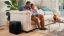 A black Sonos Sub next to a couch while a father and daughter watch TV