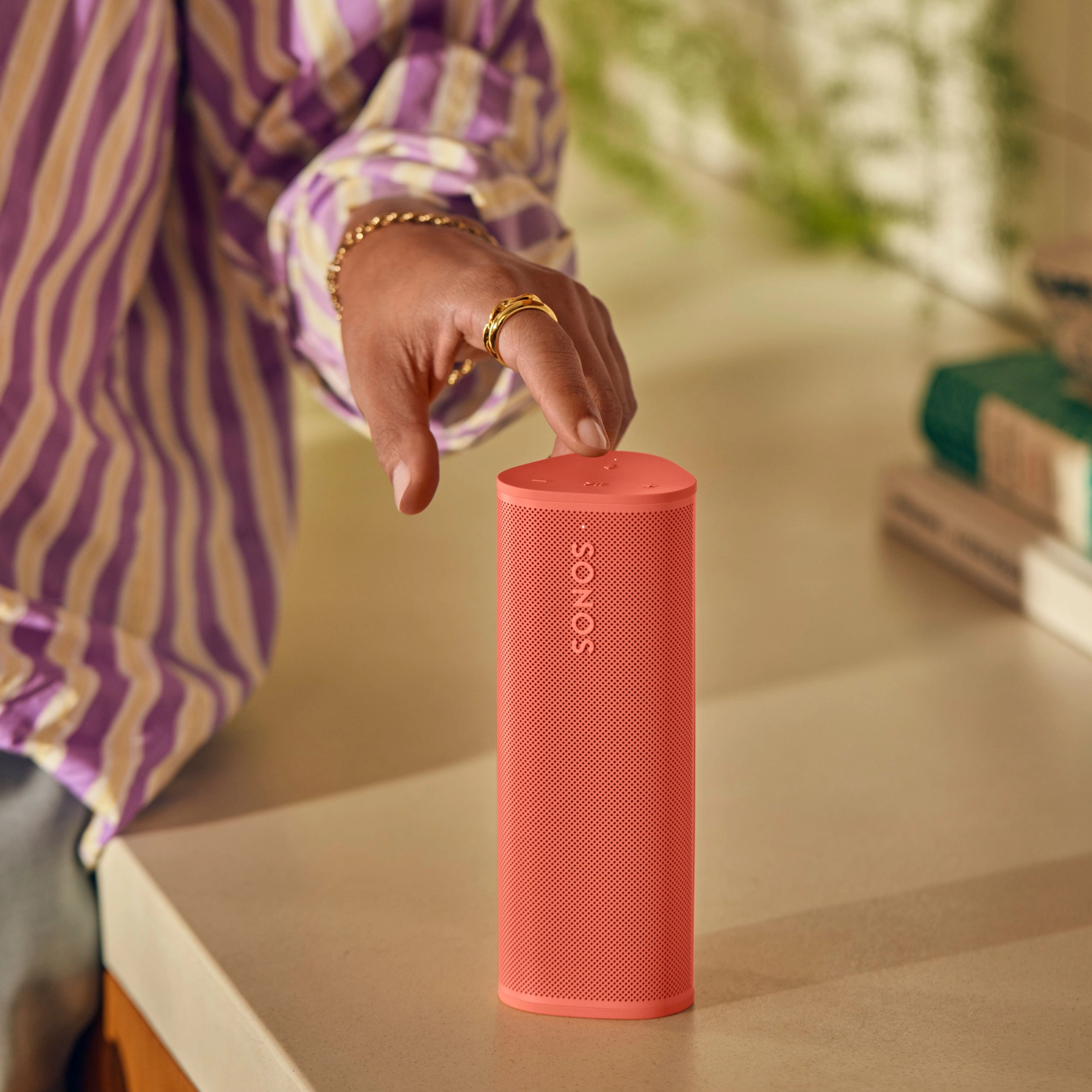 Closeup view of a hand tapping Sonos Roam 2 in Sunset